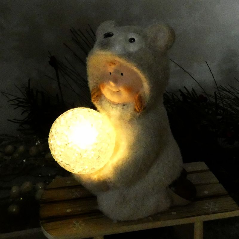 Figurka zimního dítěte- klečící holka v medvědím oblečku s LED koulí, 16 cm
