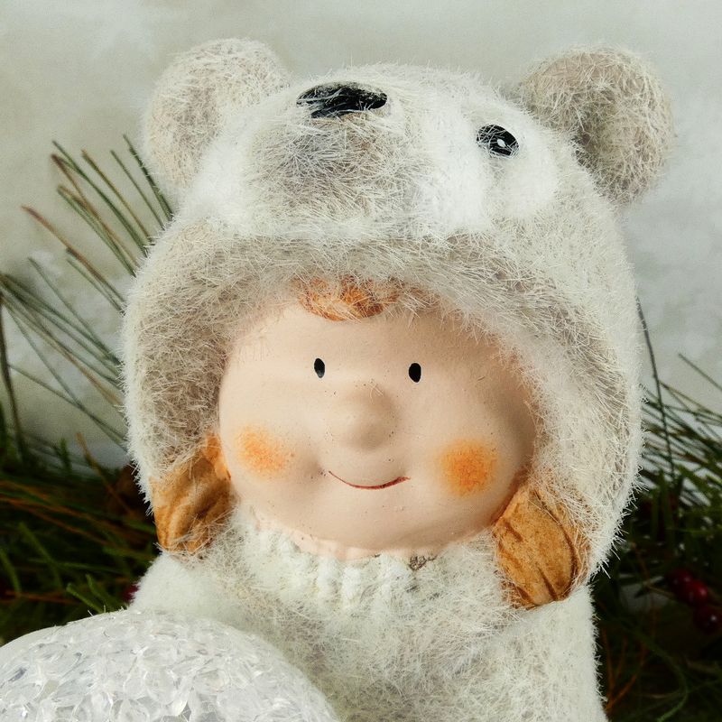 Figurka zimního dítěte- klečící holka v medvědím oblečku s LED koulí, 16 cm