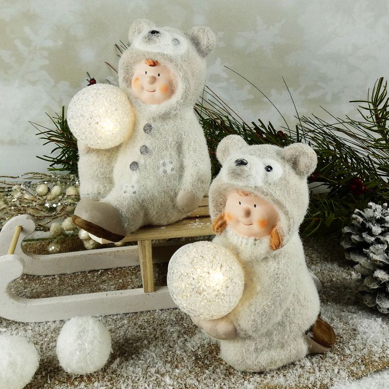 Figurka zimního dítěte- klečící holka v medvědím oblečku s LED koulí, 16 cm